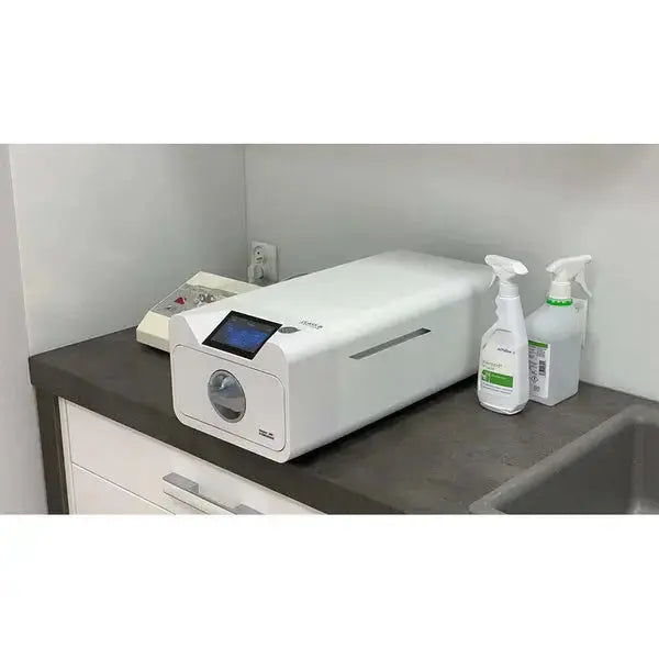 Enbio Pro Elite Class B Autoclave sterilizer on countertop with digital display and control panel, alongside cleaning spray bottles for medical and dental practices